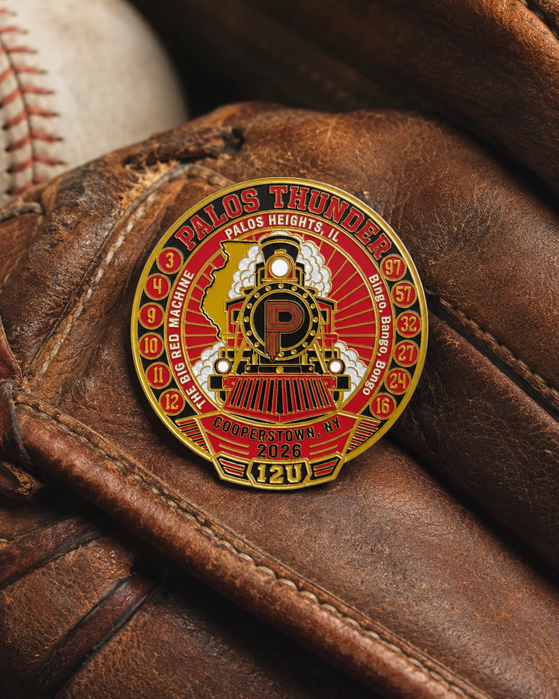Art-directed lifestyle visualization of a circular red and gold Palos Thunder train pin resting on a worn leather baseball glove.